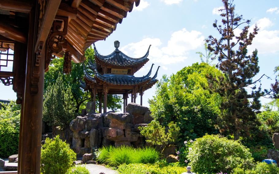 Lush green plants bloom around stones and Chinese architecture 